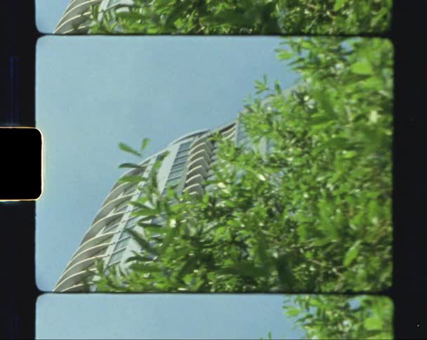 Big residential building behind a green bush caught on vintage film