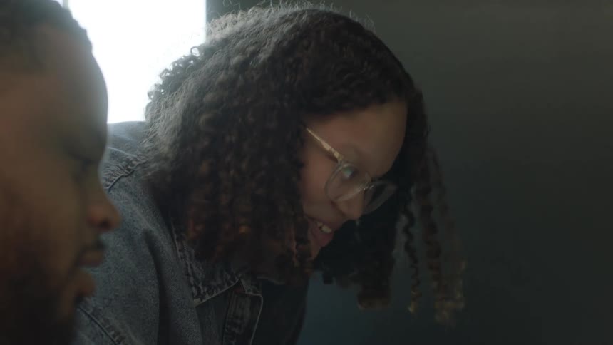 A girl smiles as her dad points at something