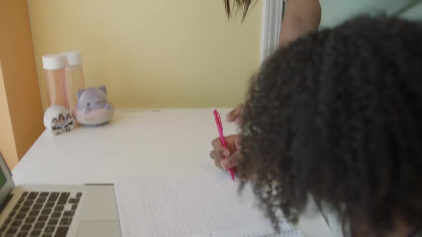 Mother helping her daughter on her homework at a table on their house