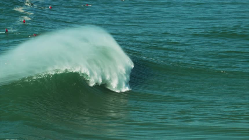 A view of a wave in the ocean with surfers around