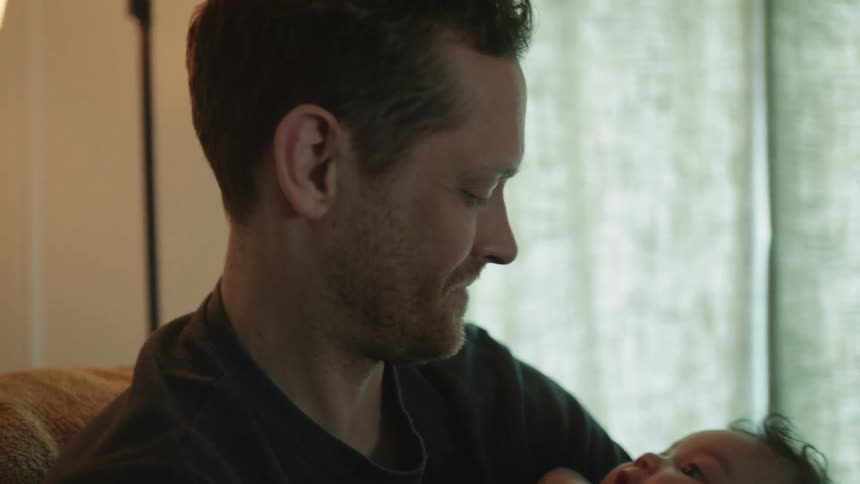 A father is rocking his child in the chair