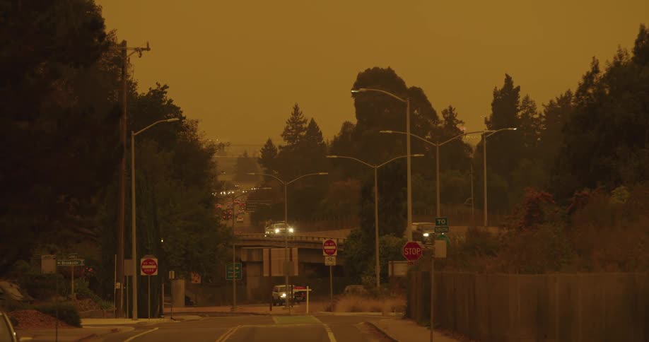 Traffic flows along highway and overpass under a red tinted sky