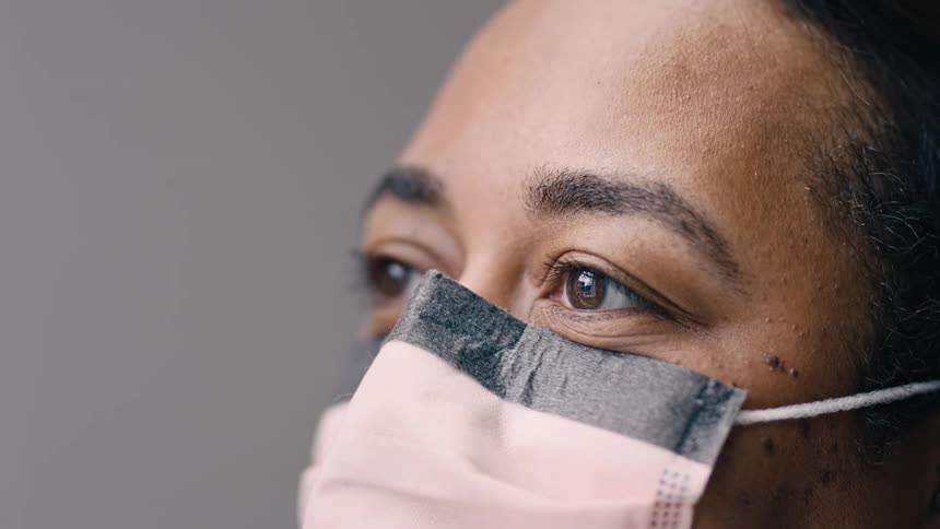 Black woman wearing a mask, chatting with nurse