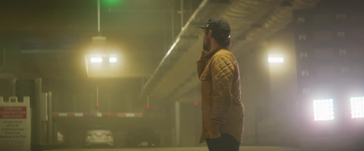 Man stands in parking garage talking on a cell phone