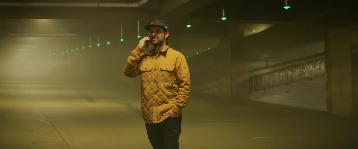 A man talks on a smartphone while pacing in a parking garage