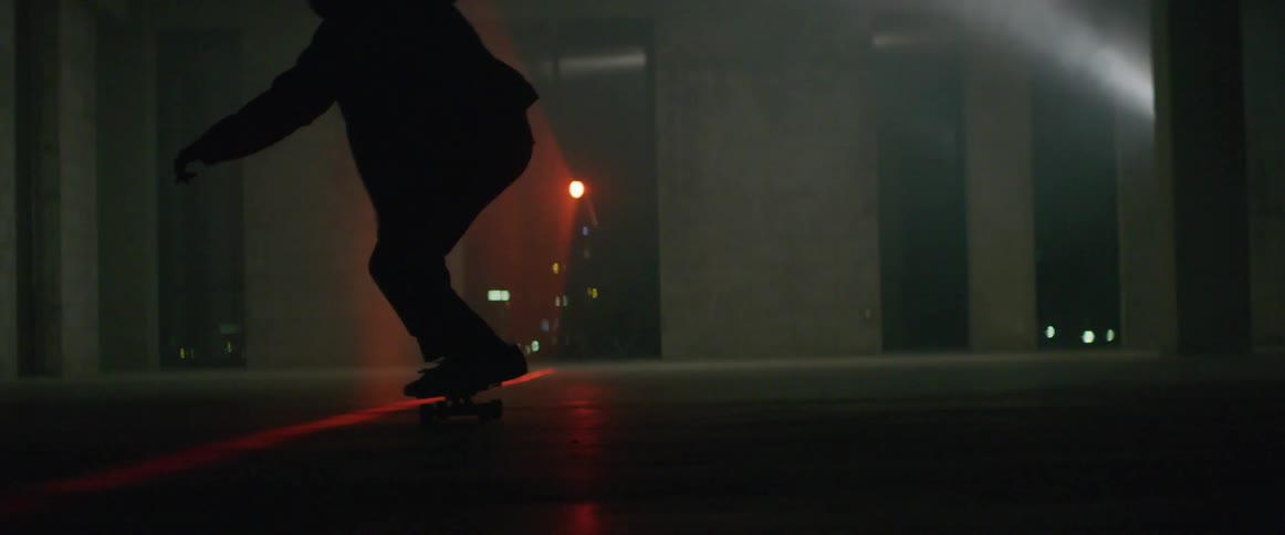 Man practicing skate stunts alone in a dark room