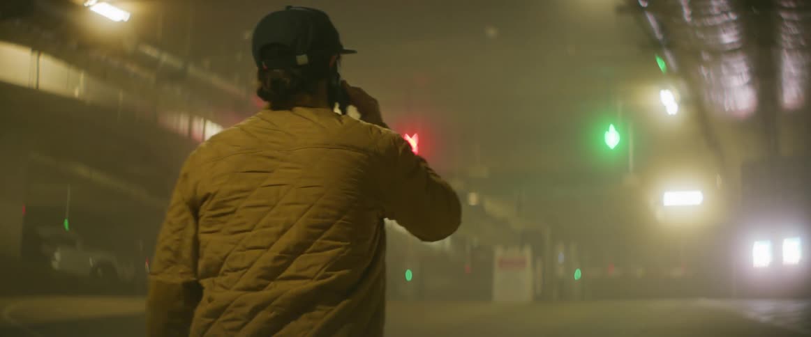 Man walks through parking garage looking around as he makes a phone call