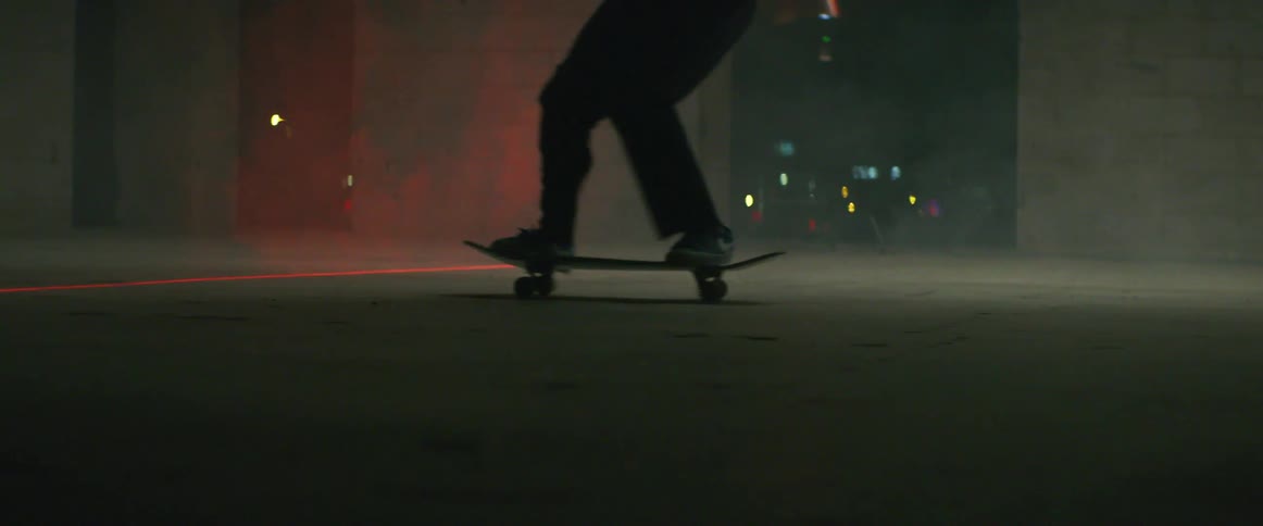 Skateboarder perform jump trick while skating through foggy area and across laser line