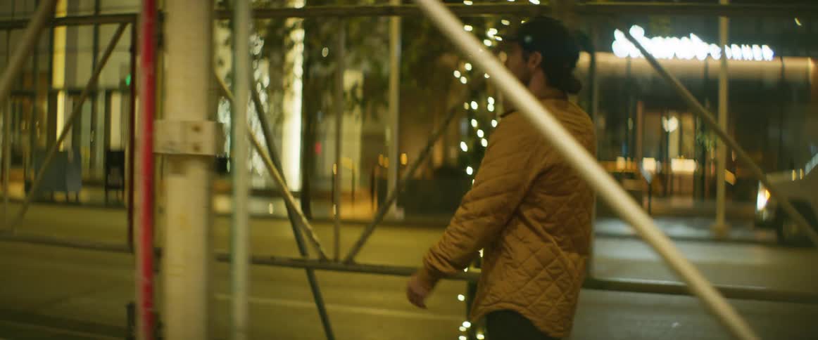 A man holds a smartphone to his ear while walking through a city at night