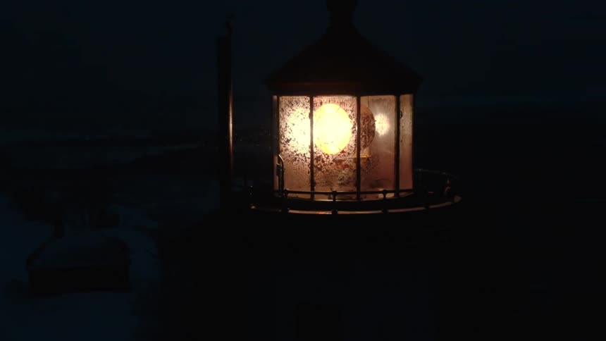 Rotating electric light in lighthouse illuminates flurries at night