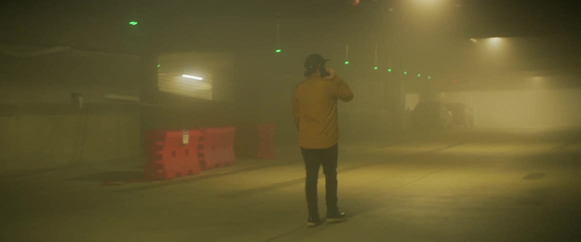 A man talks on the phone while walking through a parking garage