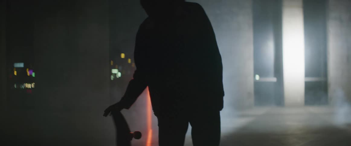 A man spins his skateboard while standing outside as a laser scans over him