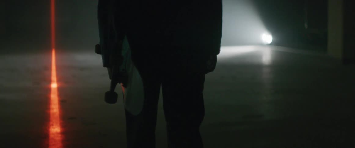A man carries his skateboard inside