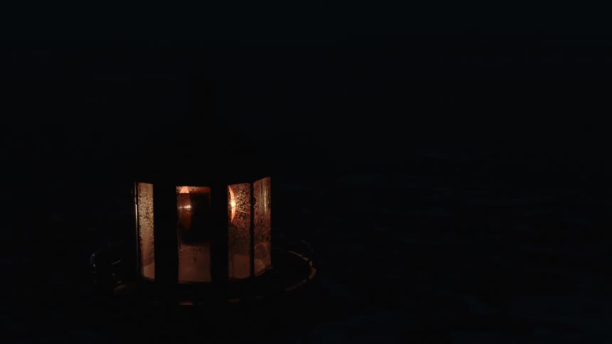 A dirty light fixture is rotating in the darkness