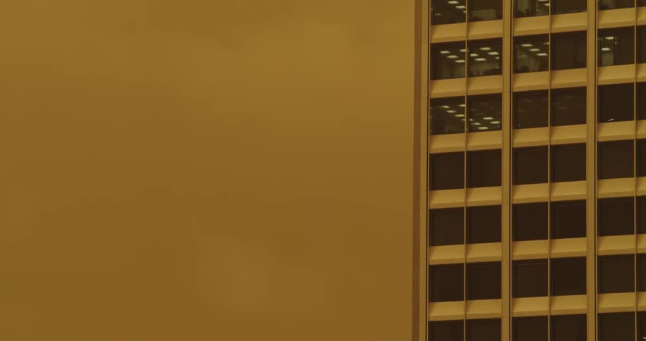 A skyscraper rises high against a smoky sky