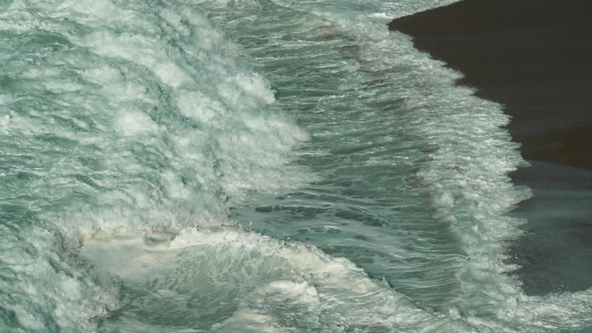 Ocean waves wash into a beach during the day