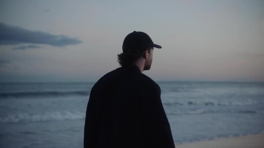 Man walks along beach as waves roll onto shore