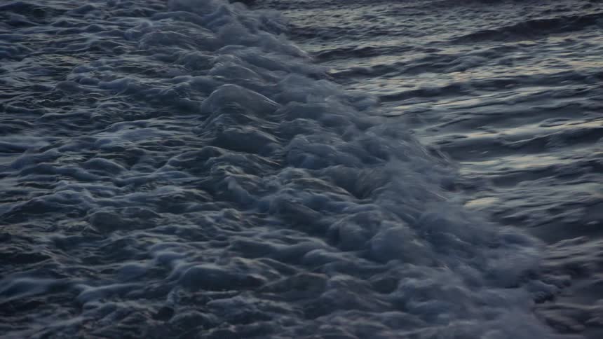 Gentle ocean wave retreating from the coast on a beach at evening