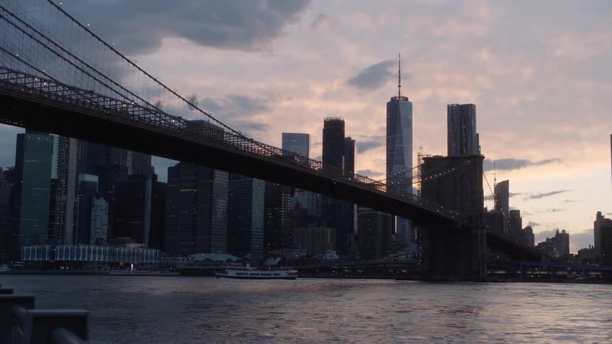 A large bridge spanning a waterway in a metropolis at sunset