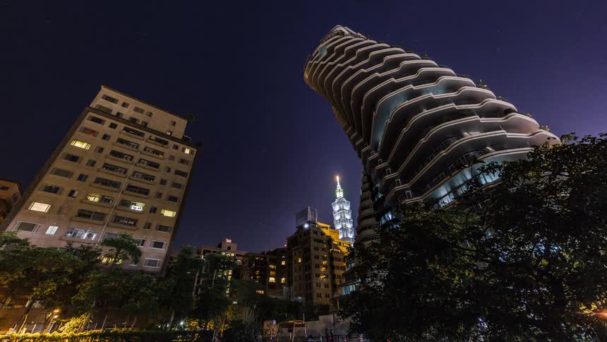 Timelapse footage of a twisted tower on a city at night