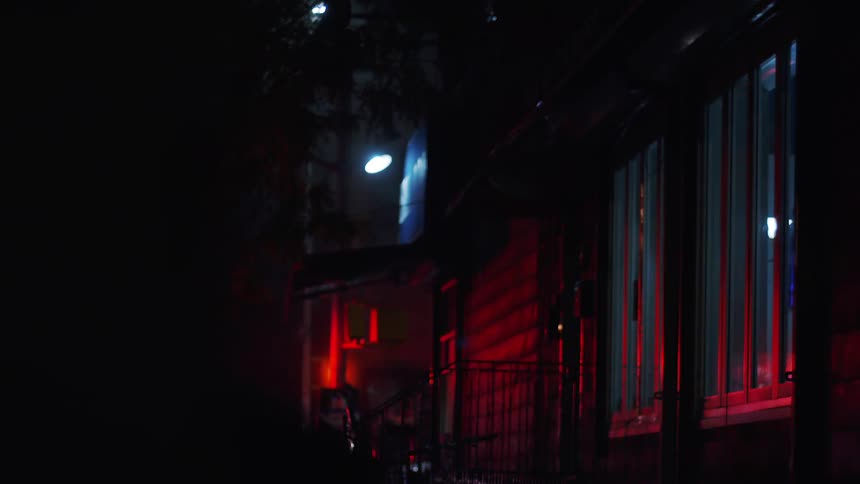 The lights from the fire truck reflect on the house at night