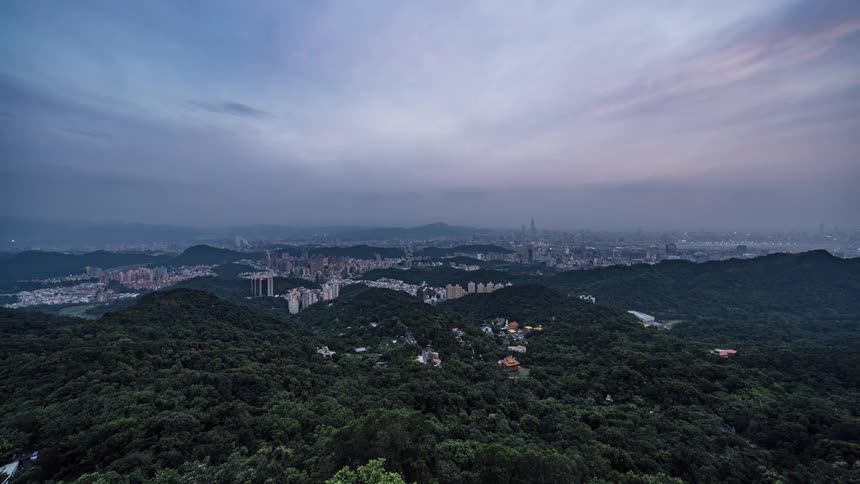 City lights brighten as night falls over city in middle of forest