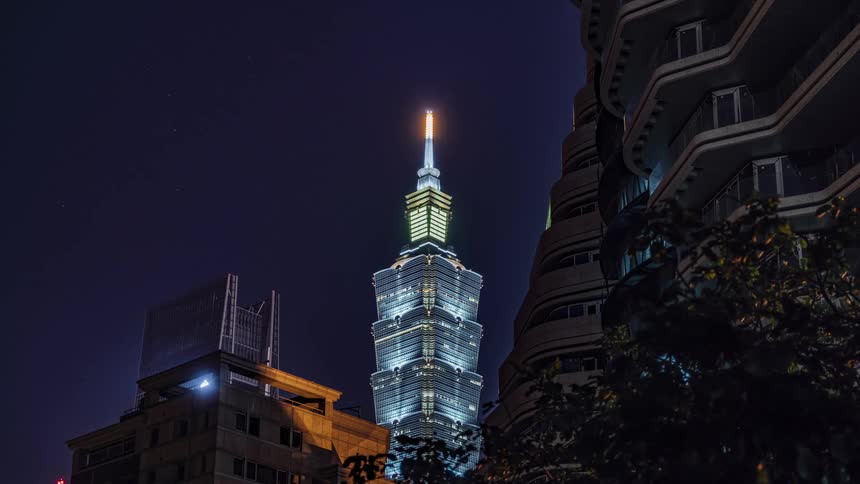 A tall skyscraper glowing in the distance on a dark night