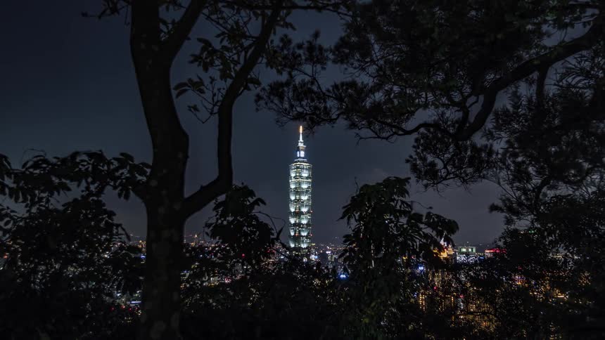 A lit up skyscraper is visible through trees