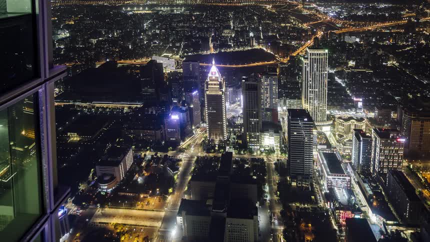 City buildings and streets shimmer with light and moving traffic at night