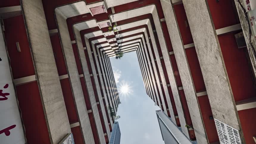 Sun shines through middle of building from light blue sky