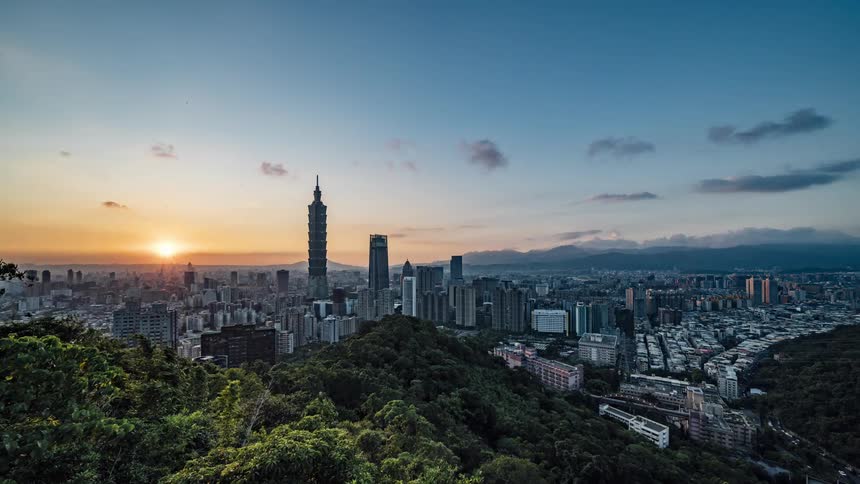 Clouds flow across sky and city lights come on as sun sets and night falls