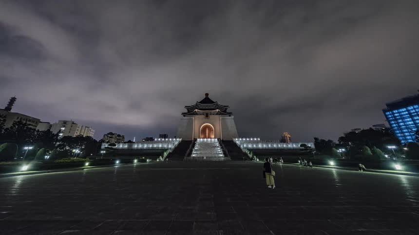 People walking around a city building on a cloudy night