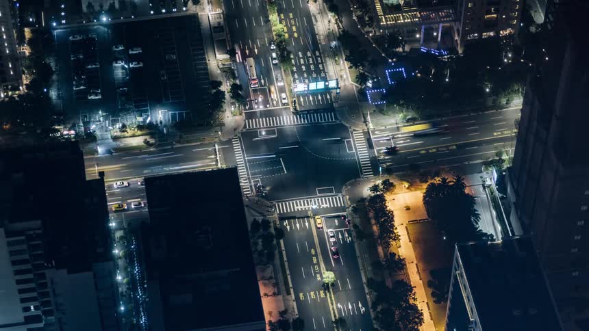 Time lapse footage of vehicles driving over an intersection in the city downtown at night