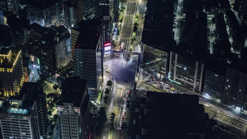 Time lapse of lights as cars drive down a city street past office buildings