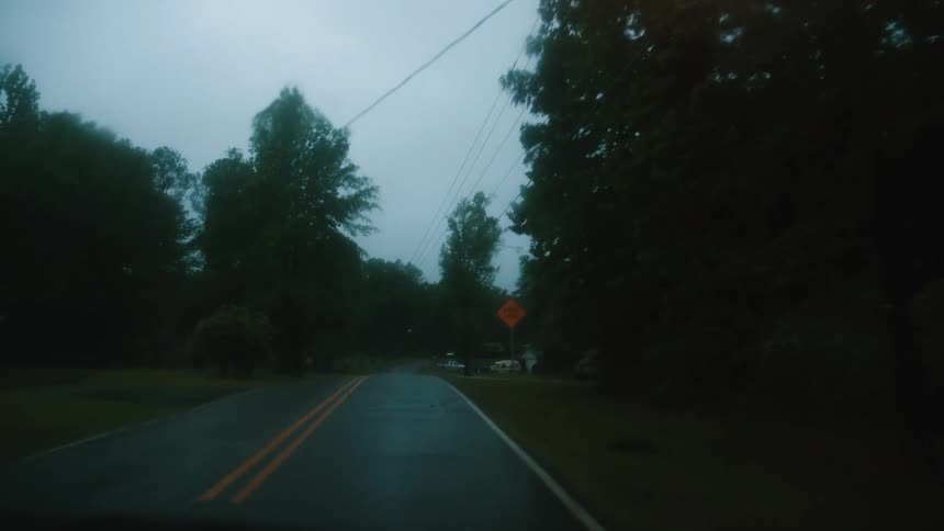 A car driving on a residential street during a rainstorm at night