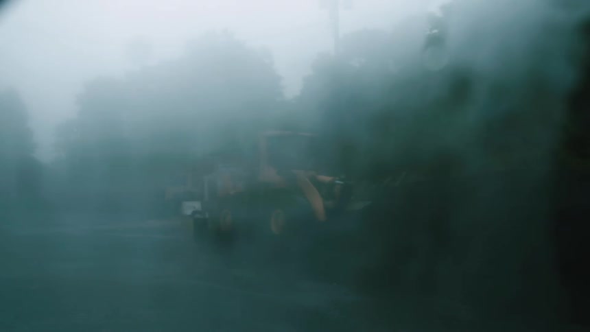 Fog obscures bulldozer parked among trees