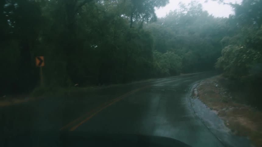 A car traveling on a rural road during a rainstorm