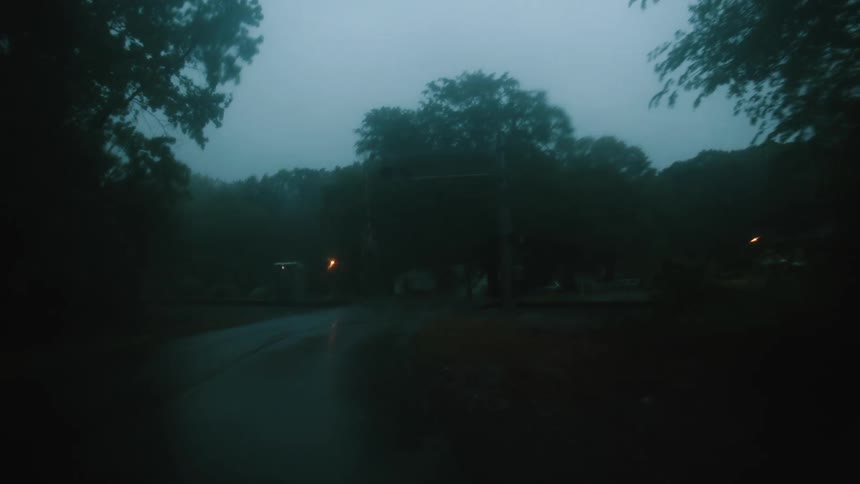 Wet road passes through neighborhood and crosses railroad tracks