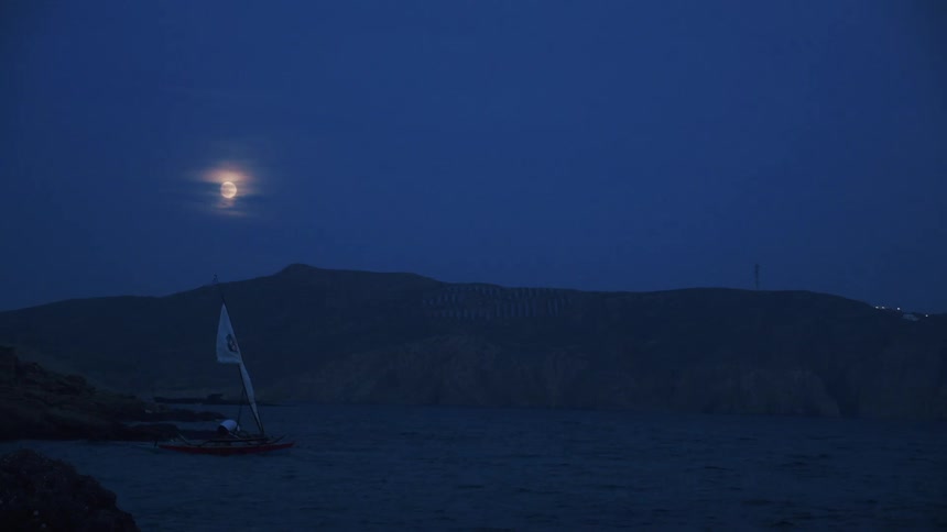 A person is driving a boat on a body of water at night