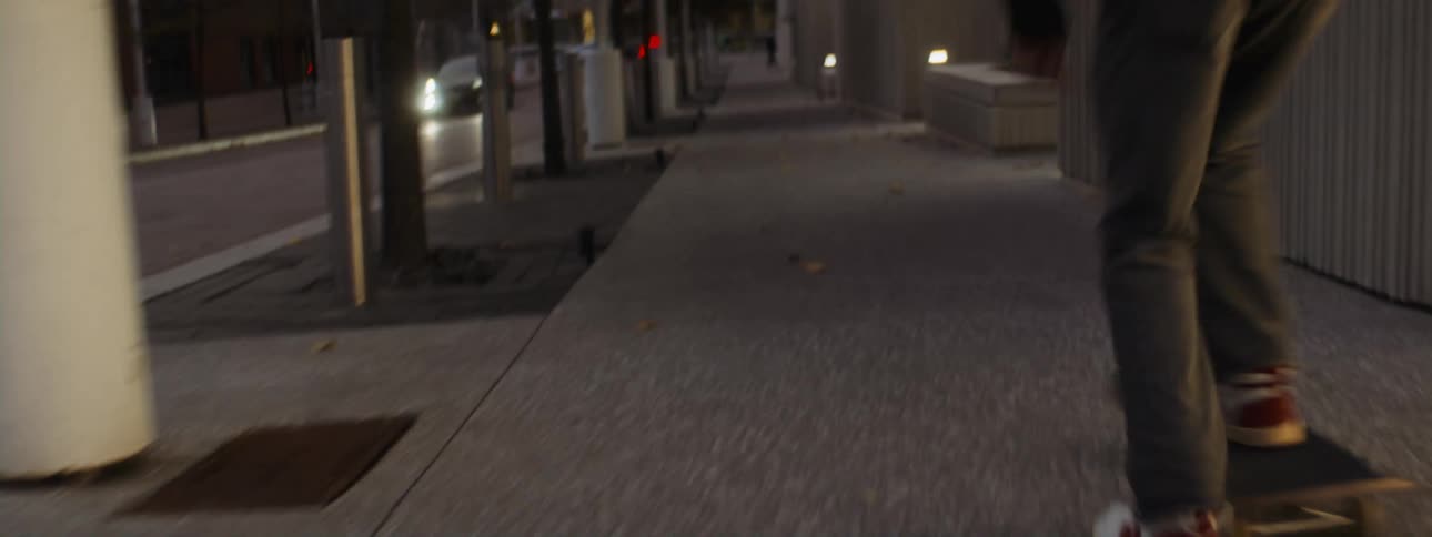 A person is skateboarding through a city at dusk