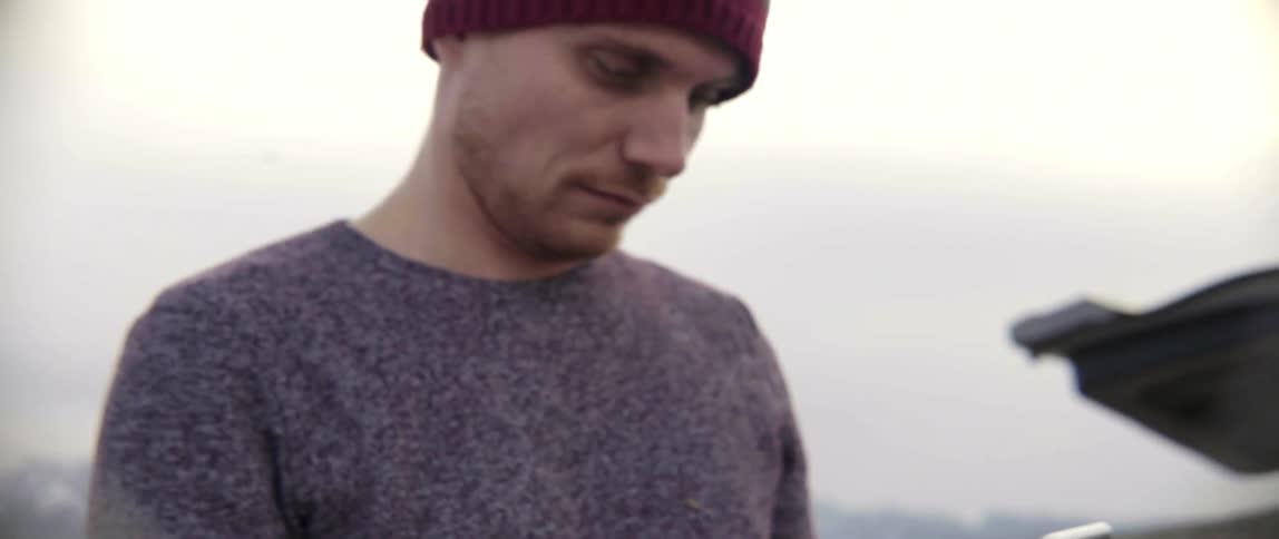 Man Outdoors Using His iPhone Tapping and Scrolling With Calm Focus in Natural Light.