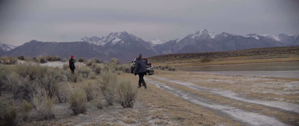 Man Walks Along Path Beside Tow Truck With Quiet Determination on a Cloudy Day.