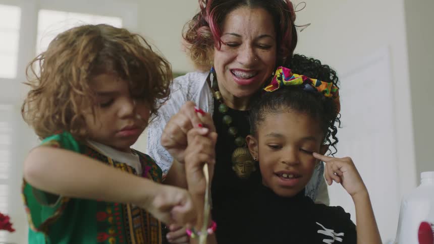 A woman helps her children bake at home