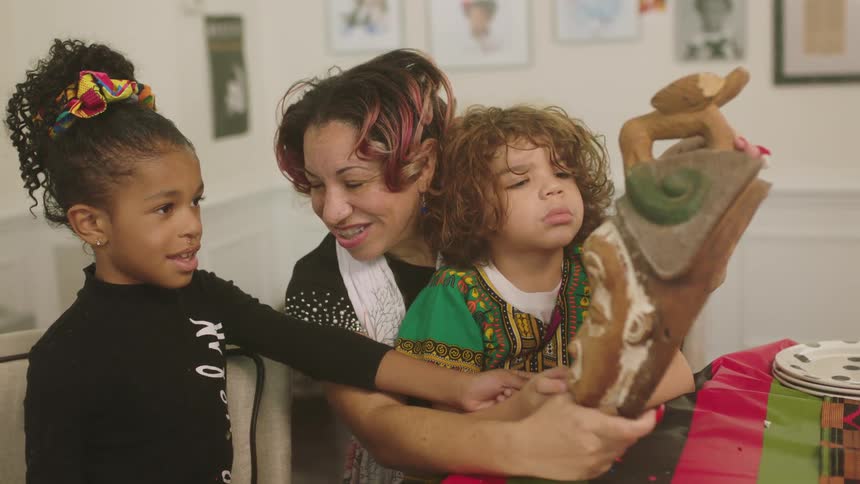 A mother and daughters looking at a mask