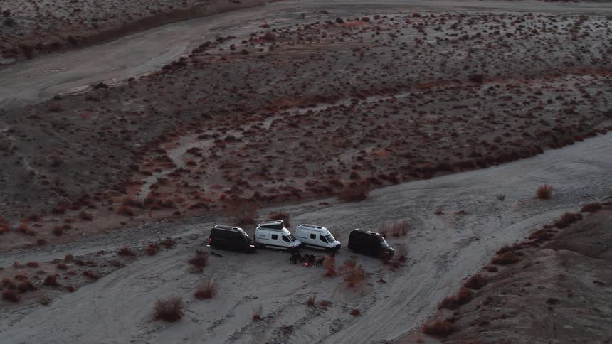 People are gathered by their vans in the desert