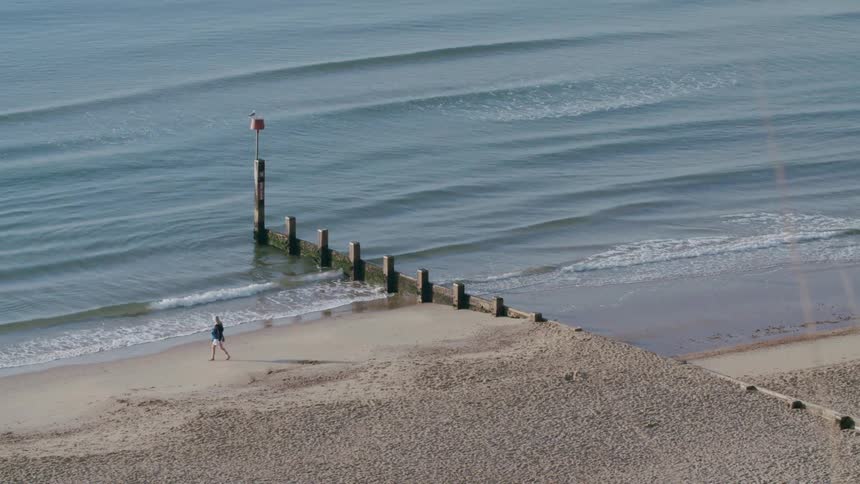 A woman on the beach walks towards the water