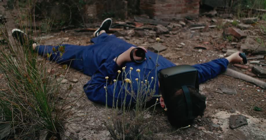 Man wearing virtual reality goggles wakes up on the ground next to a well on an abandoned building outdoors