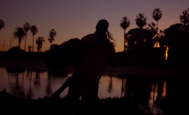 Man spinning a woman by the shoreline at the beach at sunset