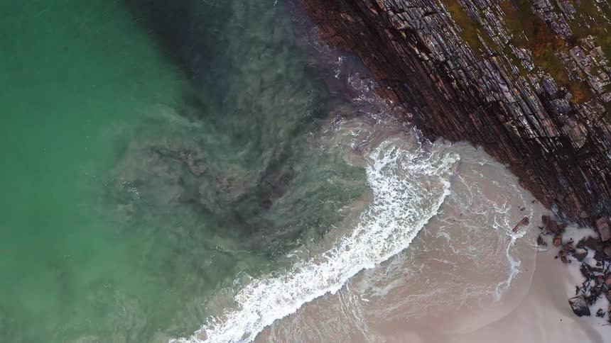 An aerial view of waves rolling in to the shore