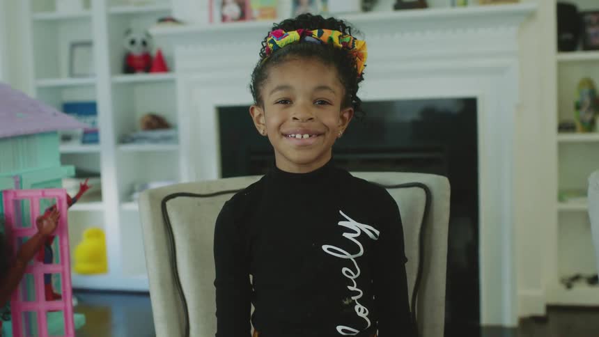 Happy little girl with a colorful bow on her head looking at the camera smiling